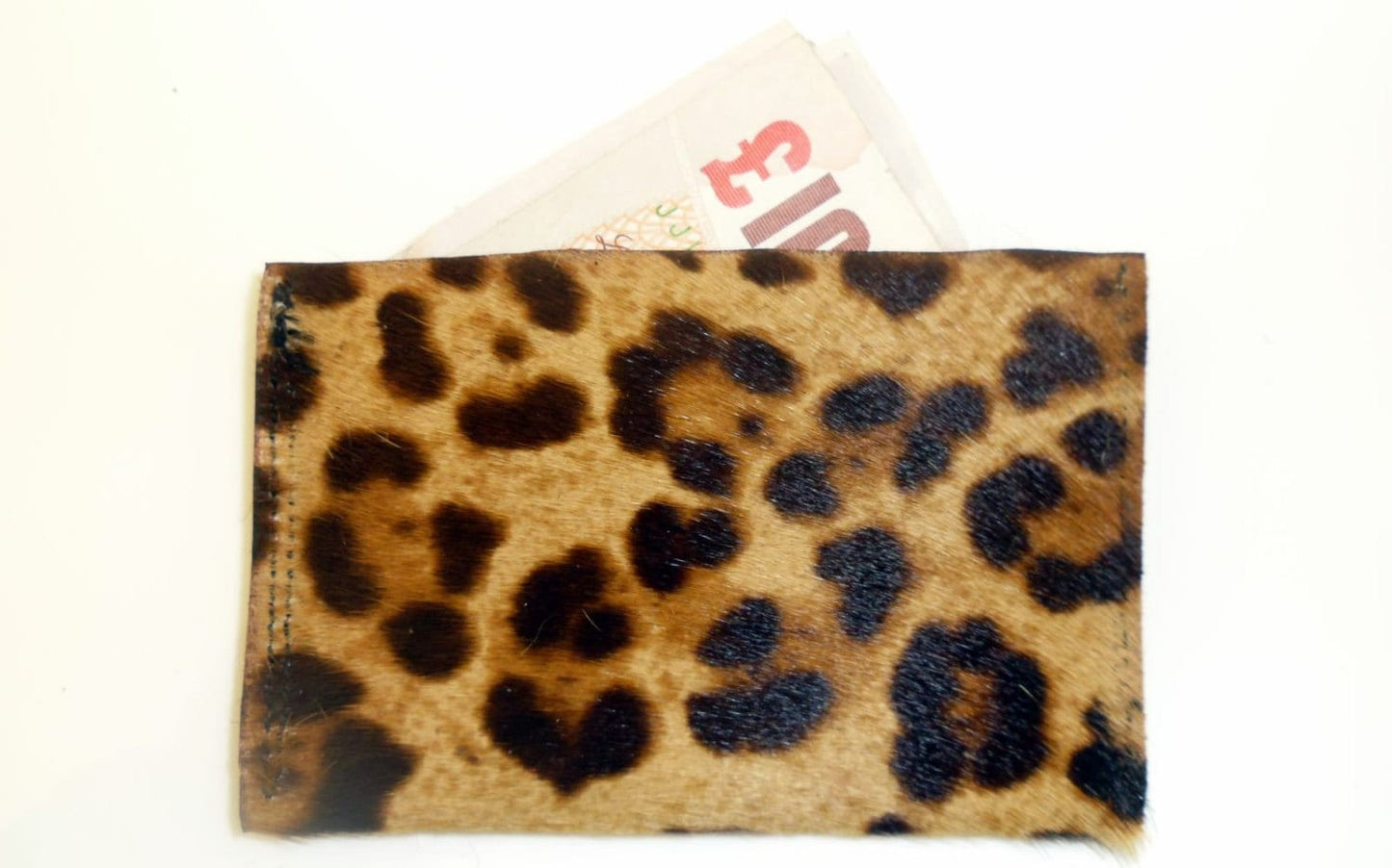 Back view of leopard print, hair-on leather credit card holder with some cash visible at the top.