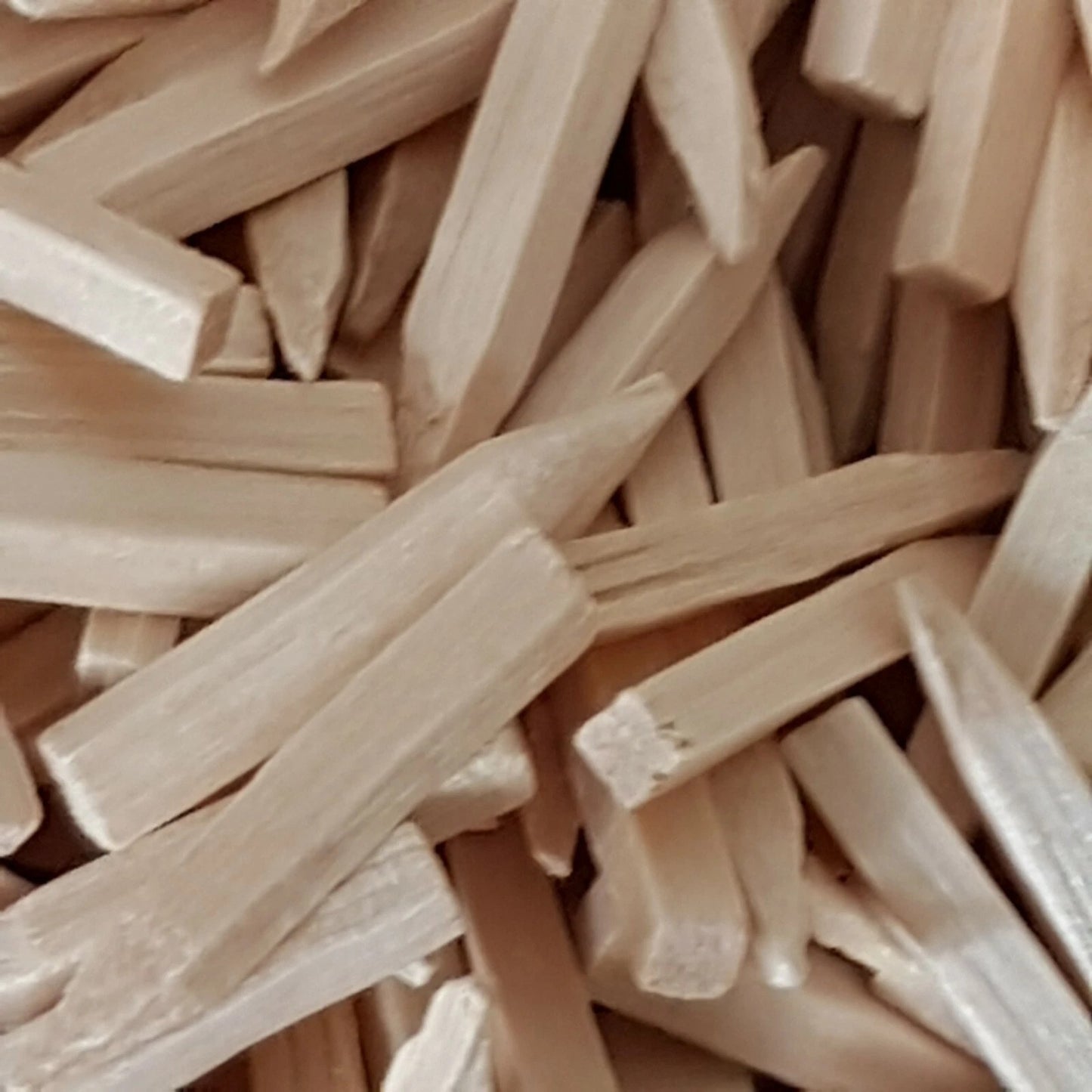 A close-up pile of light natural wood pegs or nails filling the frame.