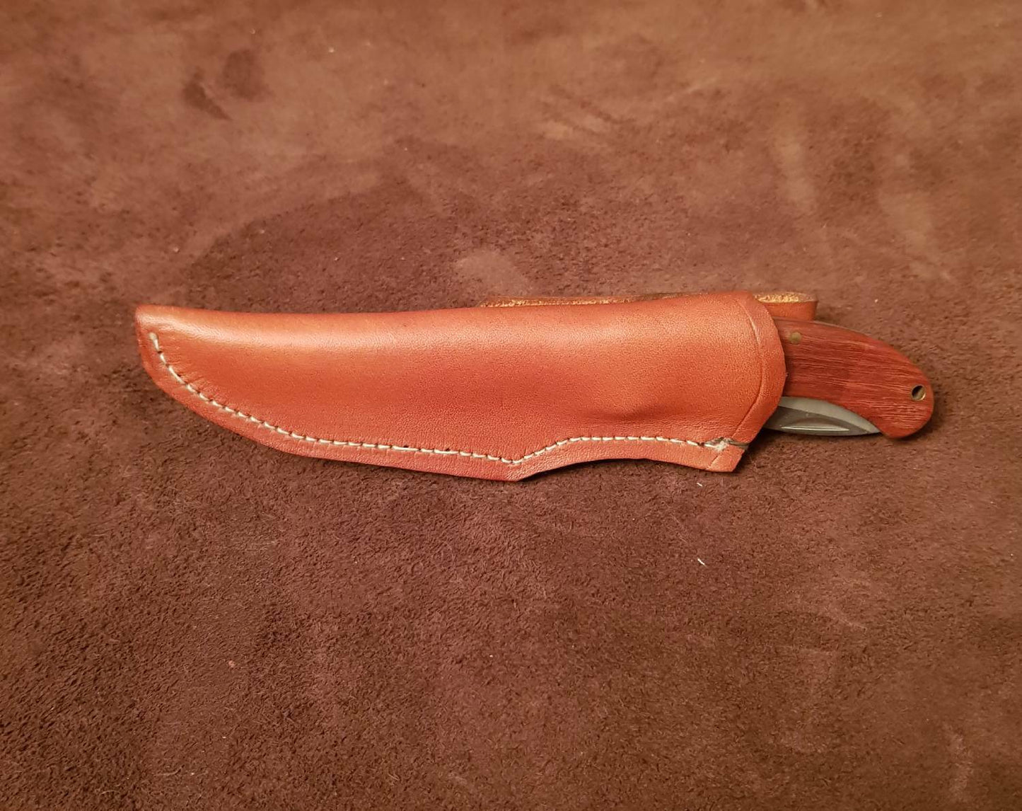 A brown leather knife sheath designed for a 6-inch friction knife, with stitching and a flap closure, placed on a textured background.