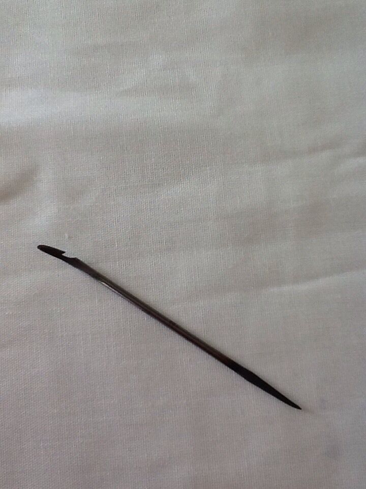 Close view of single curved hooked awl blade made of cast steel, placed on a light background.