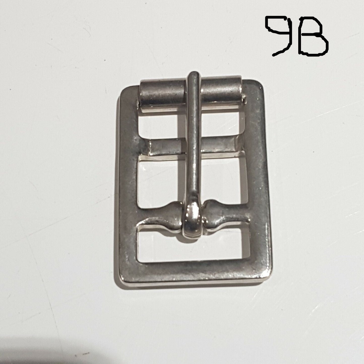 Single metal saddlery buckle with a chrome finish on a white background, labelled 9B