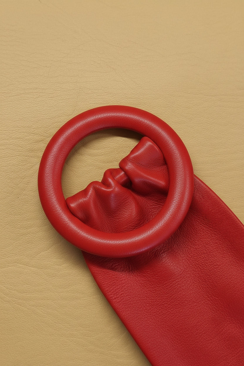 A close-up women red leather cinch belt with a leather covered ring buckle.