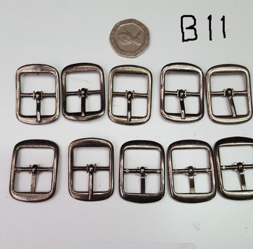 Closer view of gun metal buckles against 20 pence for size. Used for bags belts and shoes, laid out on a surface with a coin for scale reference.
