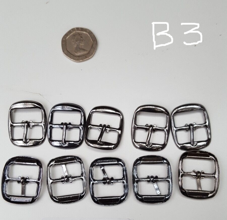 A set of gun metal buckles for bags belts and shoes, laid out on a surface with a coin for scale reference.