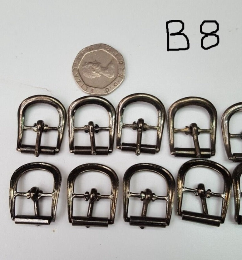 Close view of b8 gun metal buckles. Used for bags belts and shoes, laid out on a surface with a coin for scale reference.