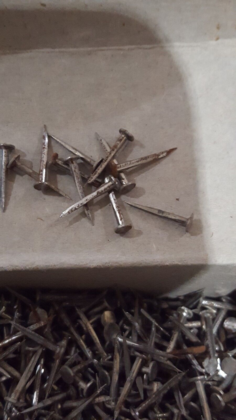 Close view of box filled with sharp metal shoe nails used for lasts and tacking in shoe making.
