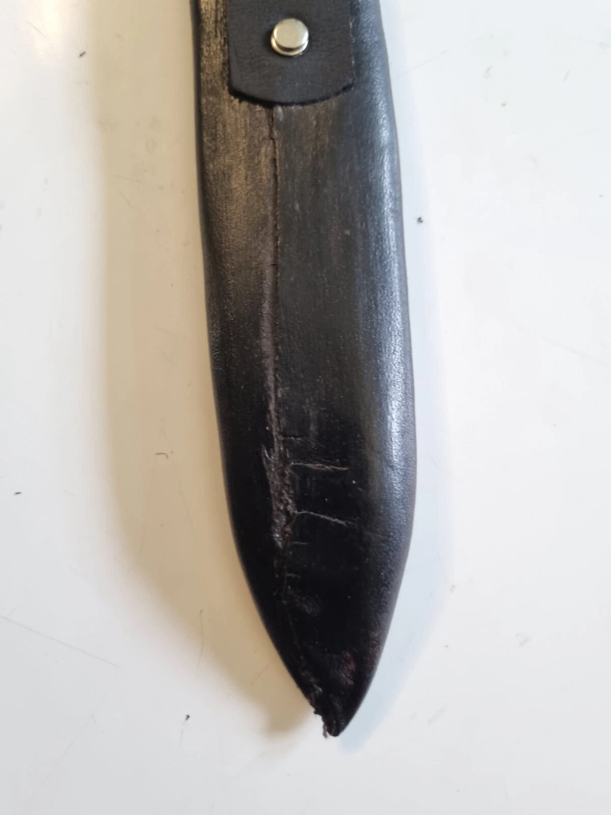 A close-up of a black leather knife sheath on a white background, showing back of the moulded sheath