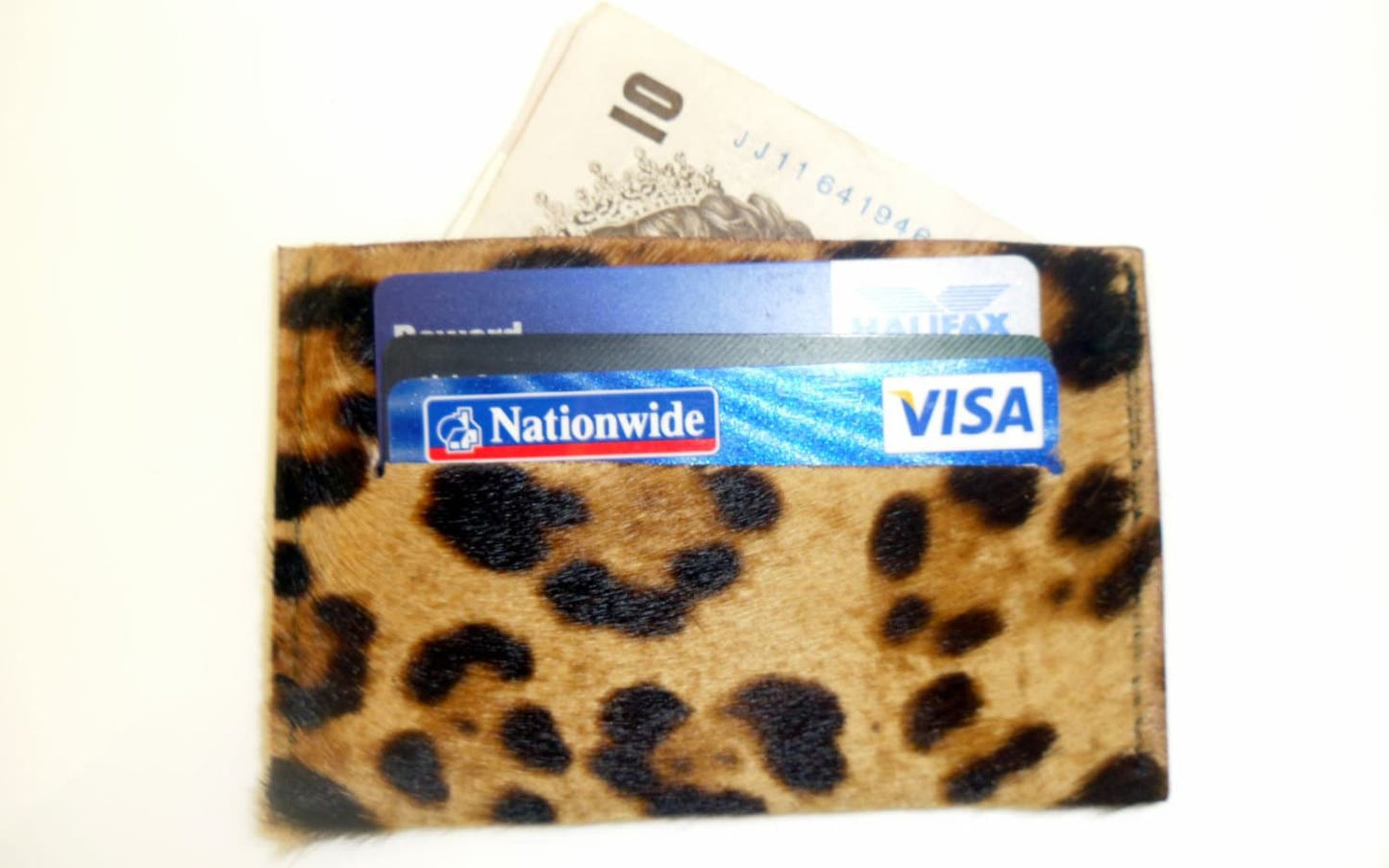 A leopard print, hair-on leather credit card holder with a blue credit card and some cash visible at the top.