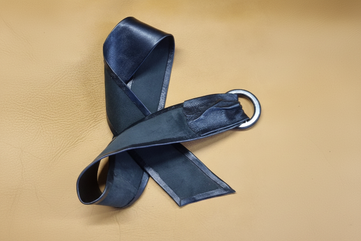 Soft black leather women belt turned over to reveal the belt. Crossed with buckle turned  over and belt showing underneath