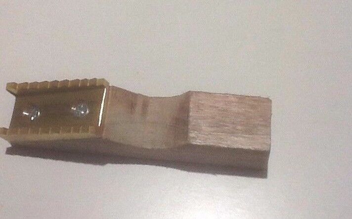 A close-up of a pure brass welt mill with a wooden base, showing the brass steps and the groove for securing the welt.