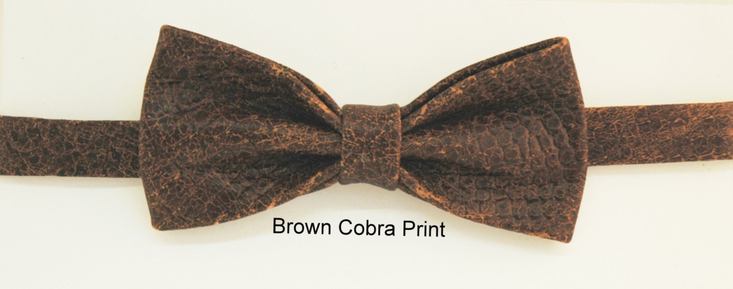A brown cobra snakeskin printed leather bow tie displayed against a neutral background.