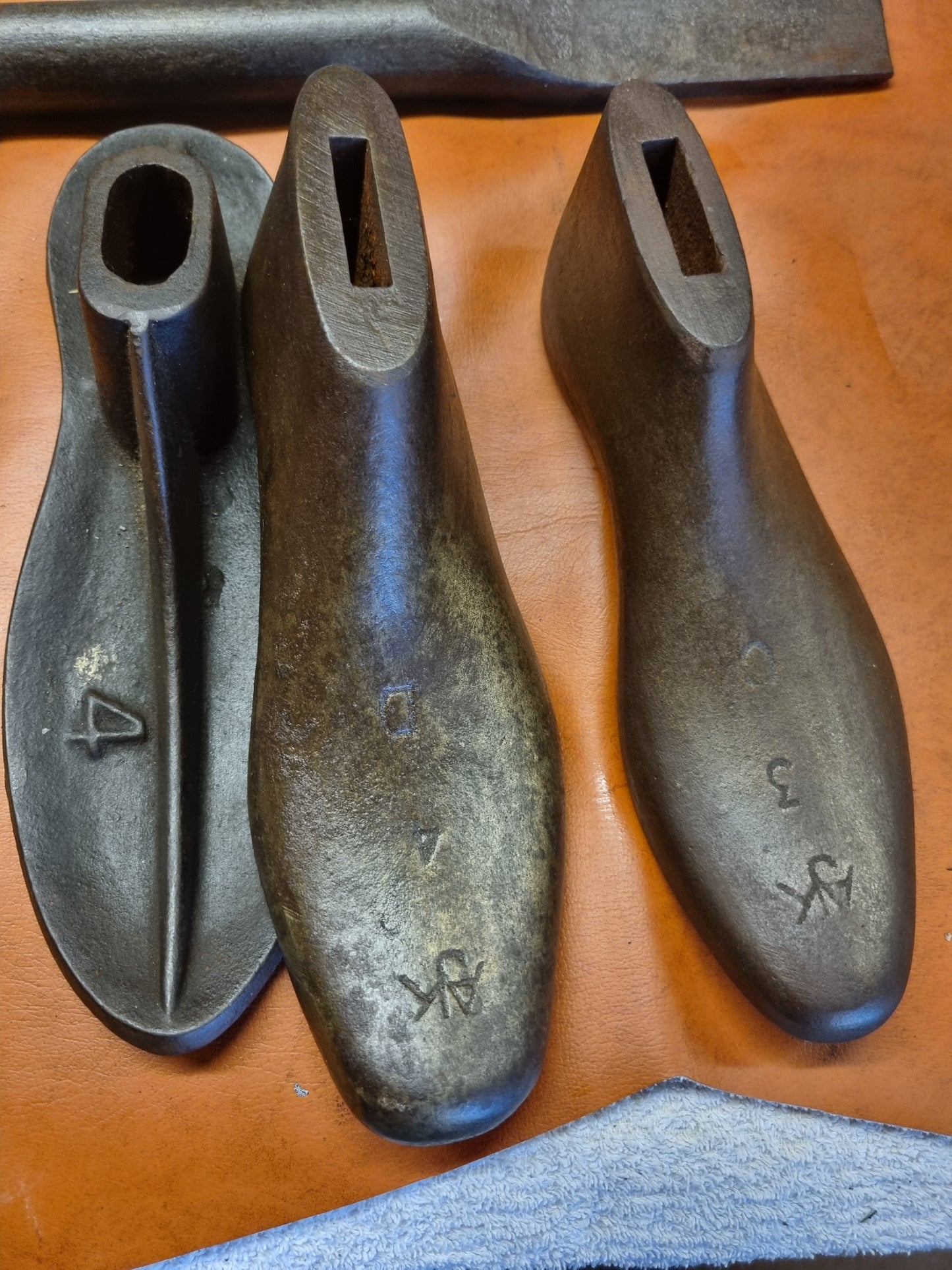 Three vintage AJK cast metal shoe lasts on a wooden surface