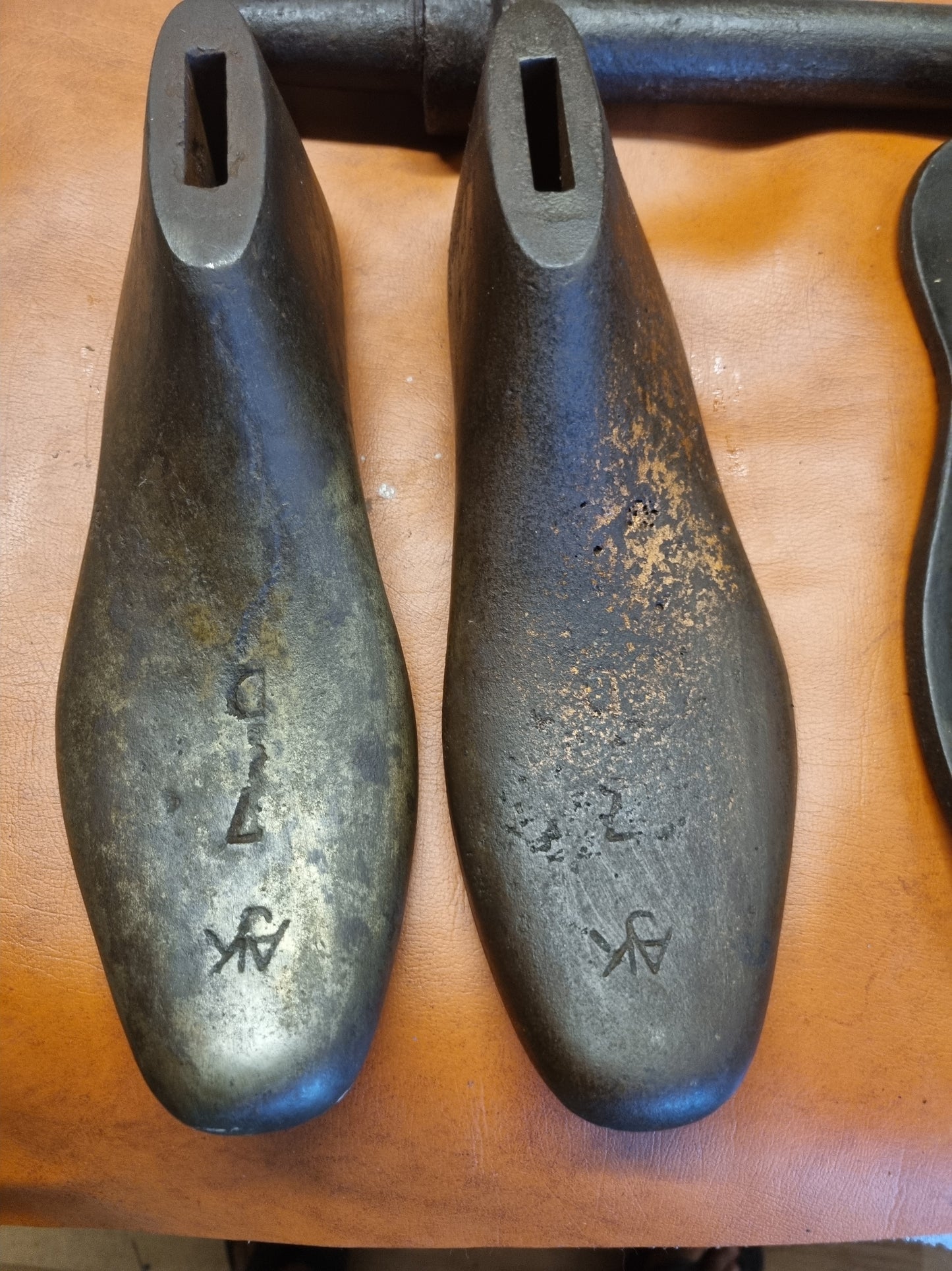 Two cast metal shoe lasts AJK size 7 objects with engraved text AJK 7 C displayed on a wooden surface