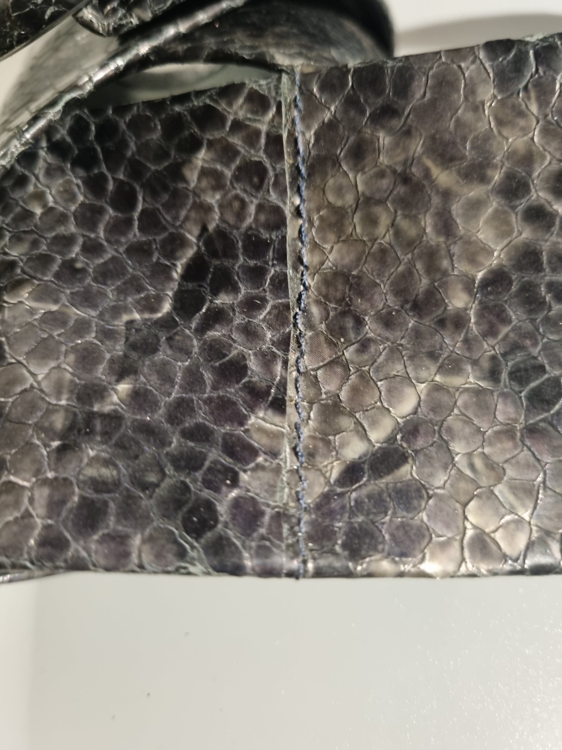 Close-up of a grey cobra snakeskin embossed women cinch belt showing visible stitching along a seam. 
