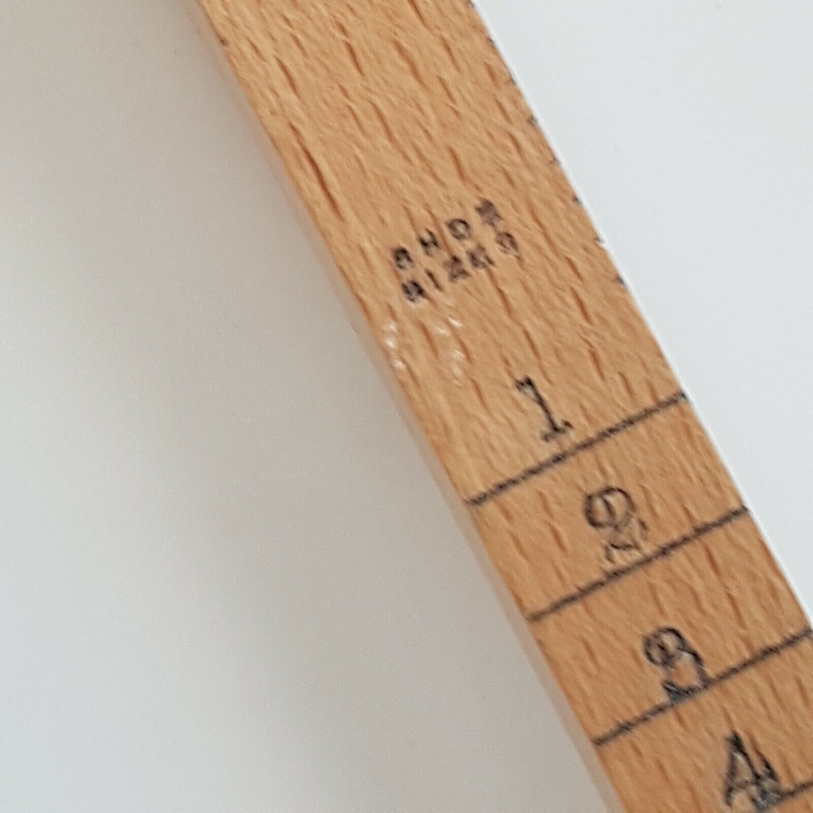 A close view of cloggers shoe size wooden stick showing shoe size numbers 1 to 4, placed on a white surface.