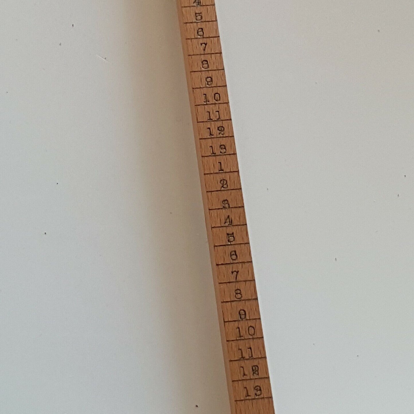 A close view of cloggers scale showing shoe size numbers 4 to 13, placed on a white surface.