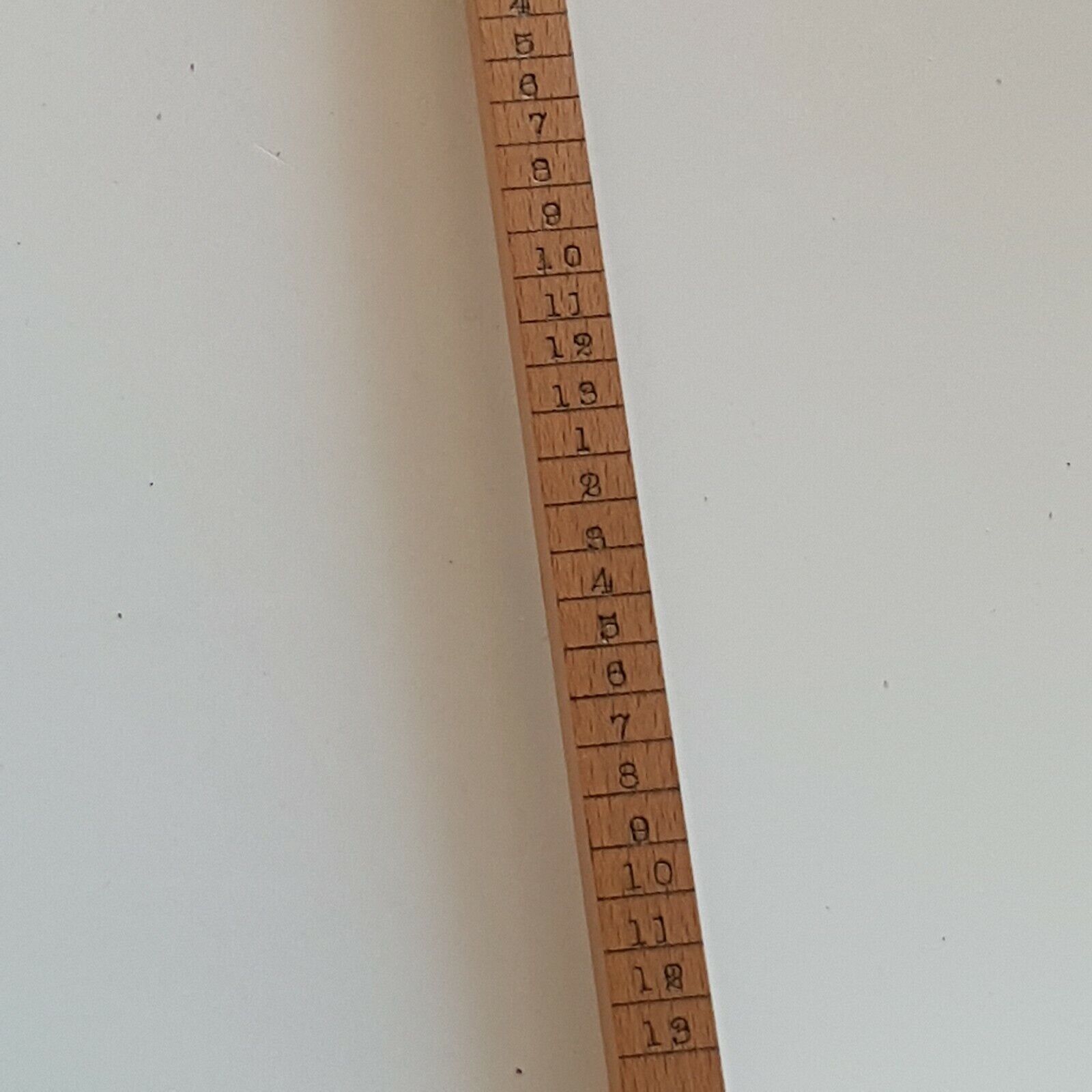 A close view of cloggers scale showing shoe size numbers 4 to 13, placed on a white surface.
