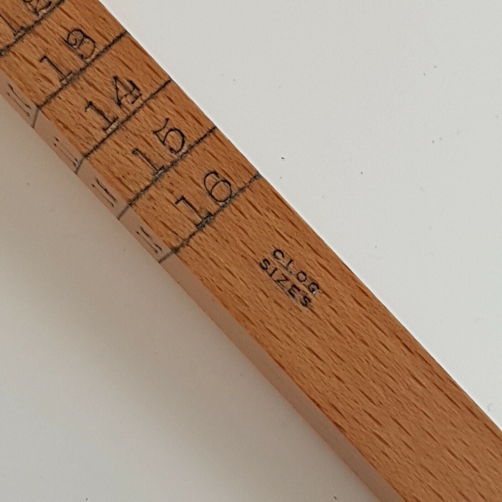 A close view of cloggers scale showing numbers 13 to 16, placed on a white surface.