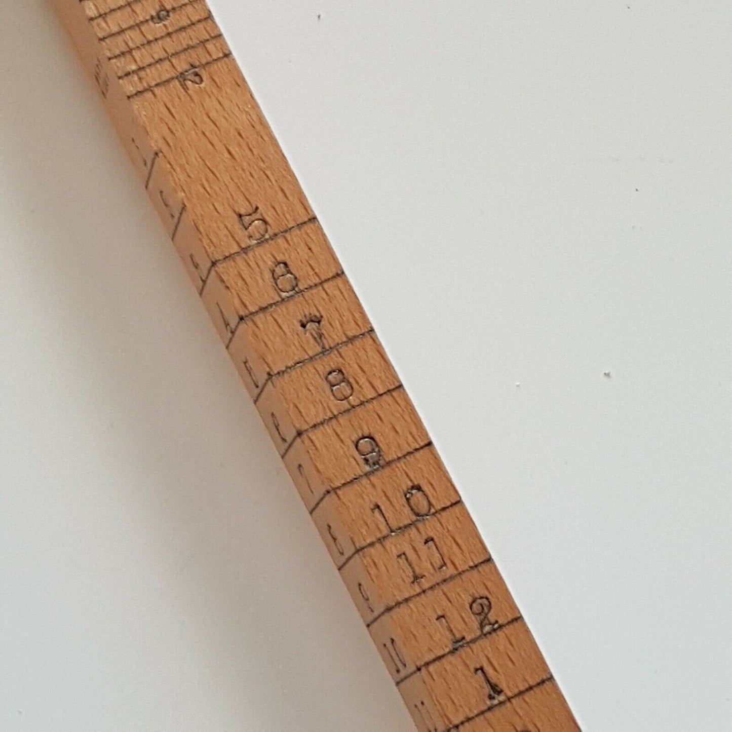 A close view of cloggers wooden stick scale showing numbers 5 to 13, placed on a white surface.
