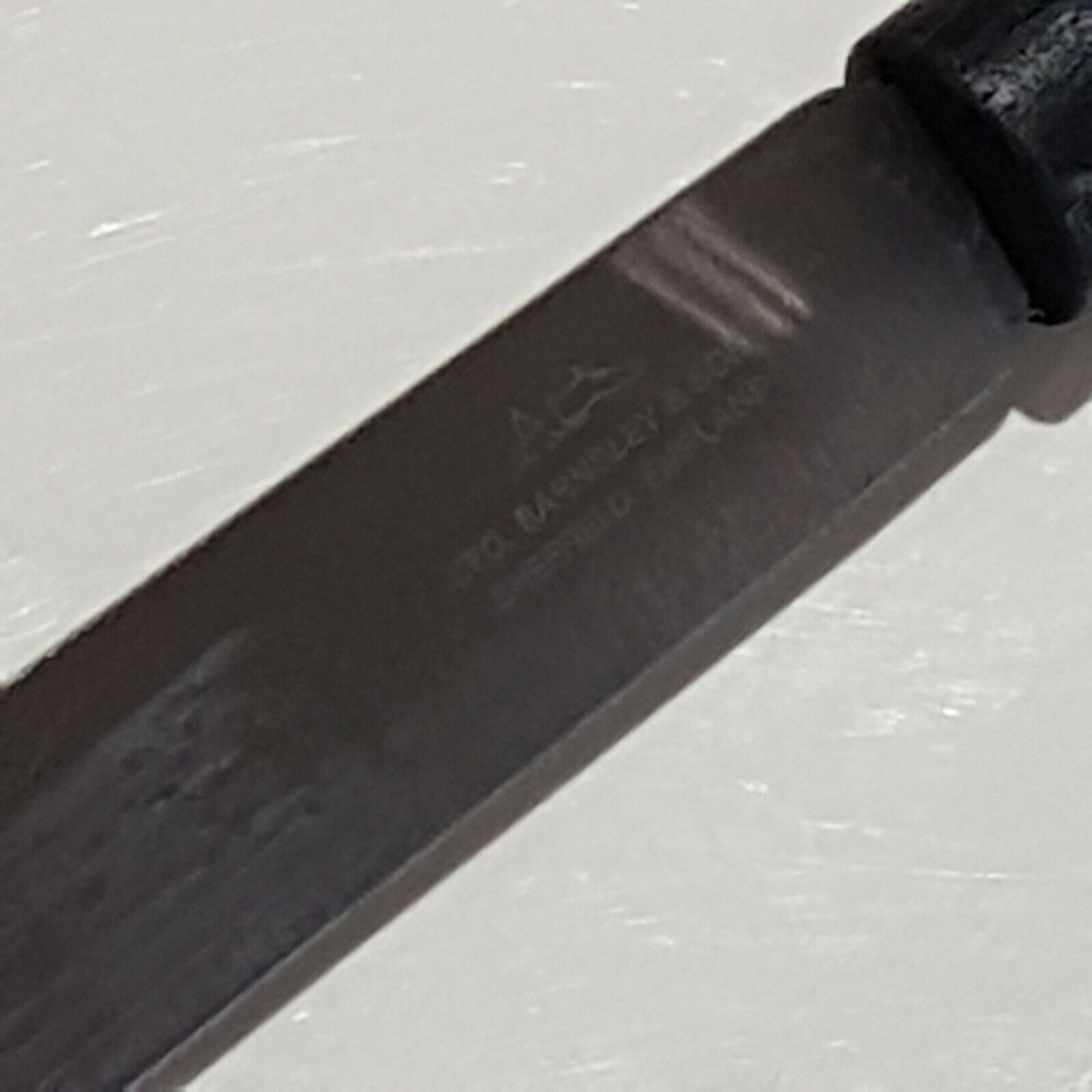 Close view broad point heel parring knife displaying makers logo on white background