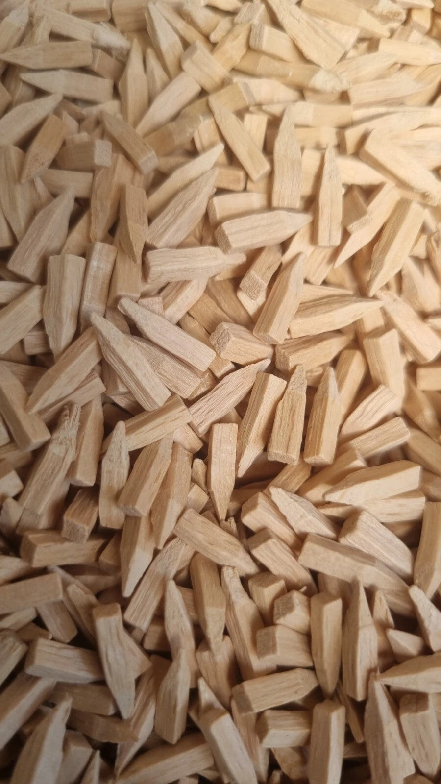 A close-up view of many small light wood pegs or wooden nails scattered densely across the frame.