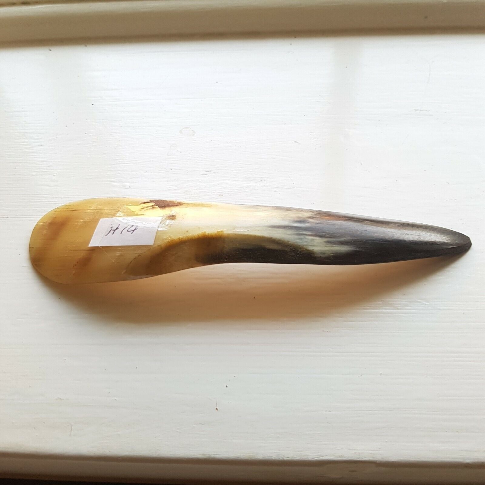 A curved cow horn titled H14 used for leather finishing tasks such as opening sewn welts, burnishing, and polishing.