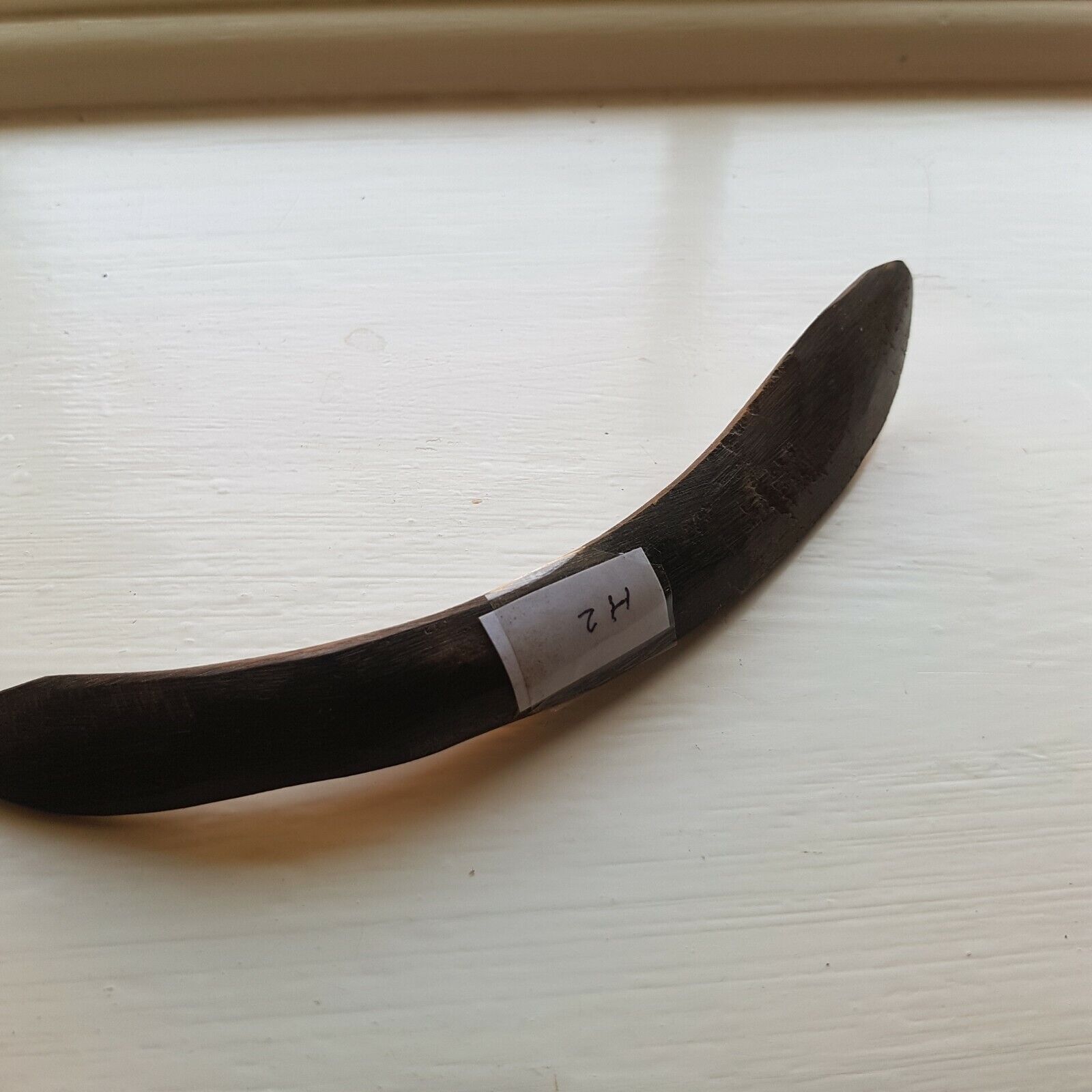A curved cow horn used for leather finishing tasks such as opening sewn welts, burnishing, and polishing.