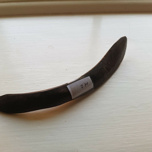 A curved cow horn used for leather finishing tasks such as opening sewn welts, burnishing, and polishing.