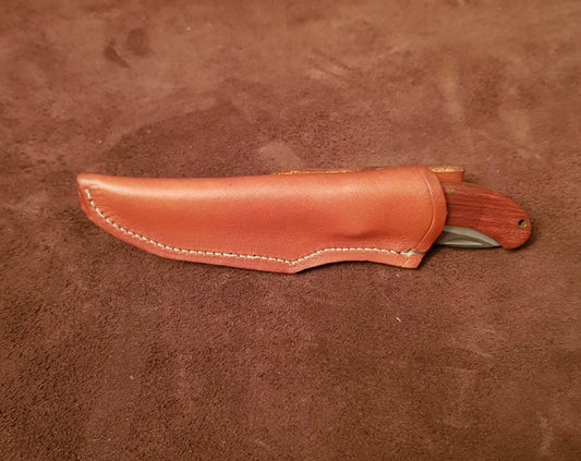 A brown leather knife sheath designed for a 6-inch friction knife, with stitching and a flap closure, placed on a textured background.