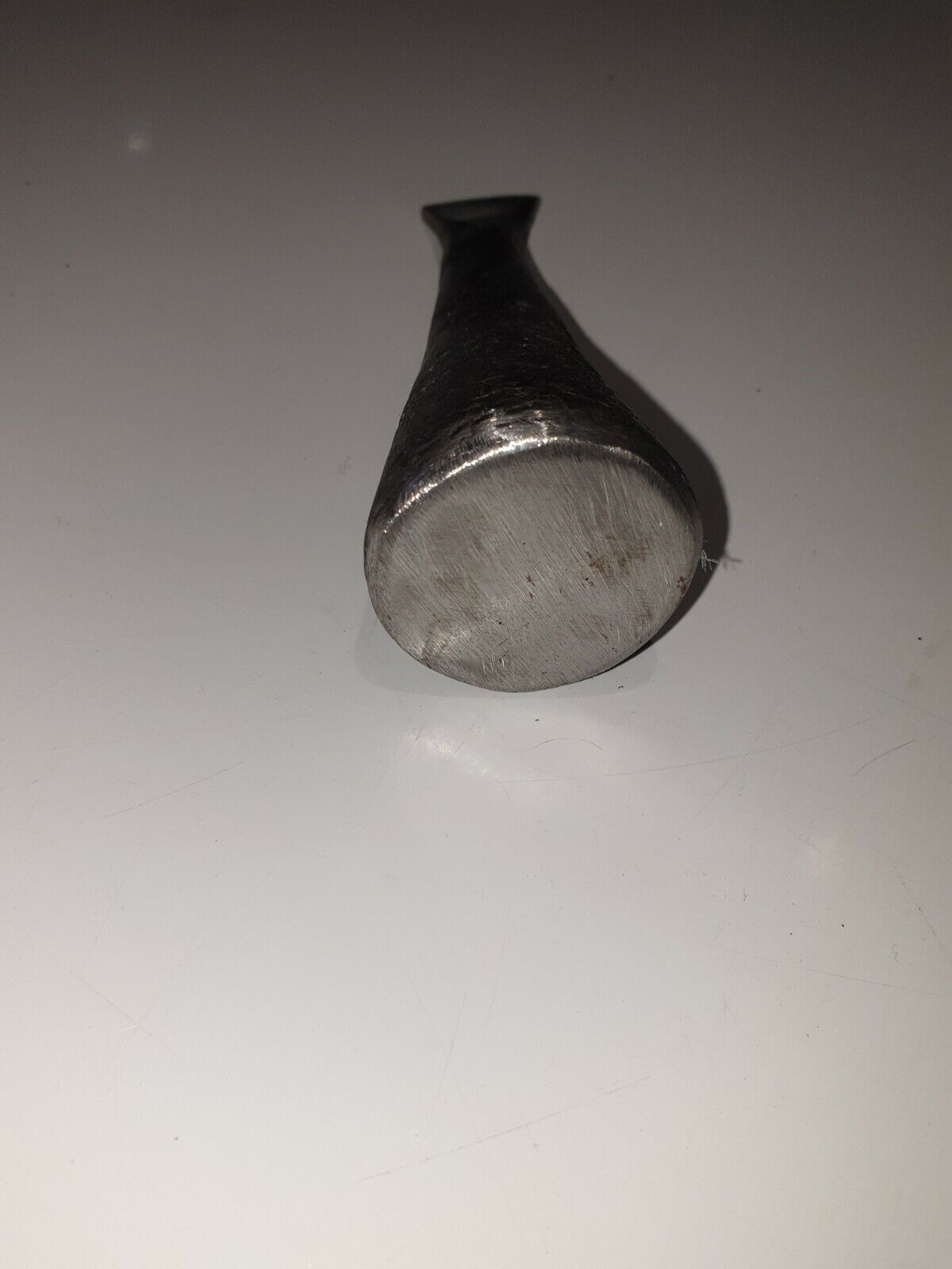 close view of cast iron folding hammer head shown lying down on white surface