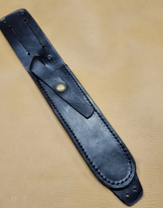 A black leather knife sheath with a brass snap button, laid diagonally on a tan leather background.