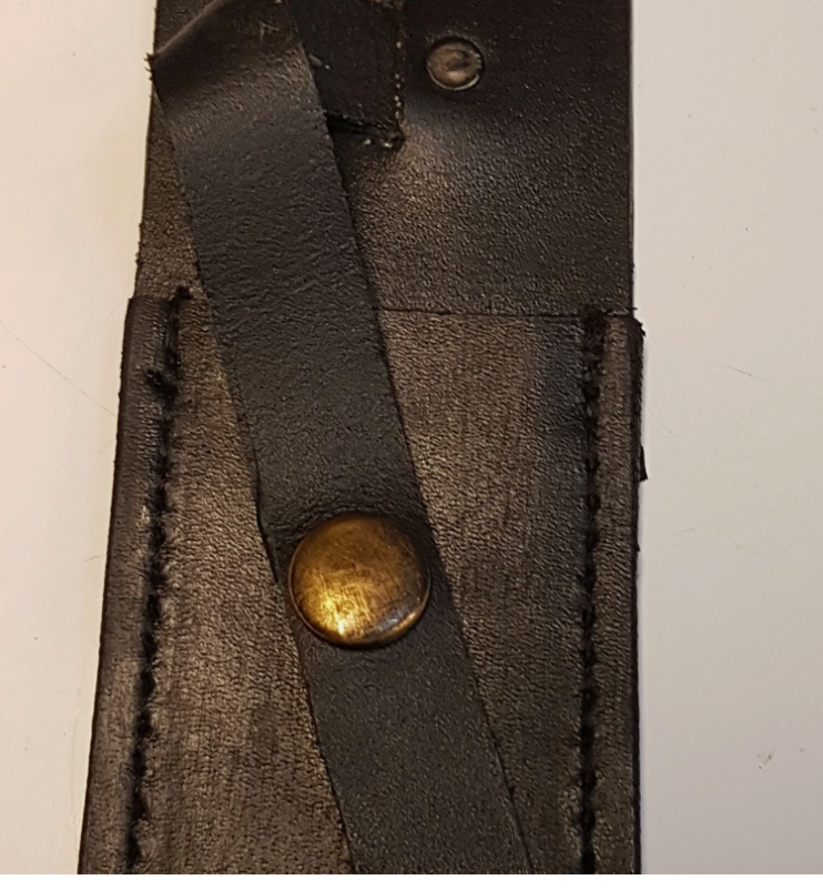 A close-up of a black leather strap with a brass snap button closure, shown against a plain off-white background.