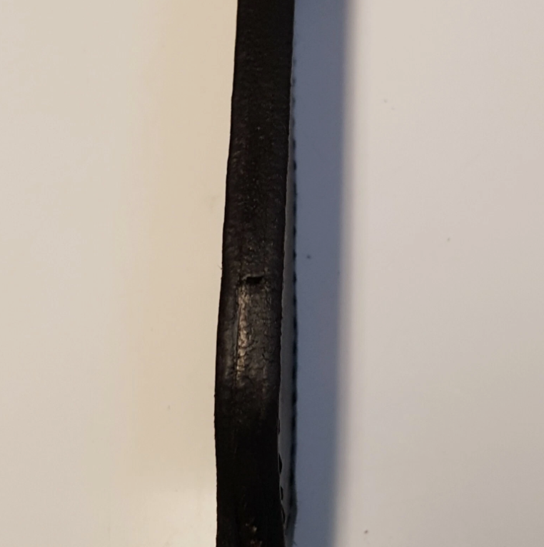 A close-up of a black leather sheath welt standing vertically against a plain off-white background.
