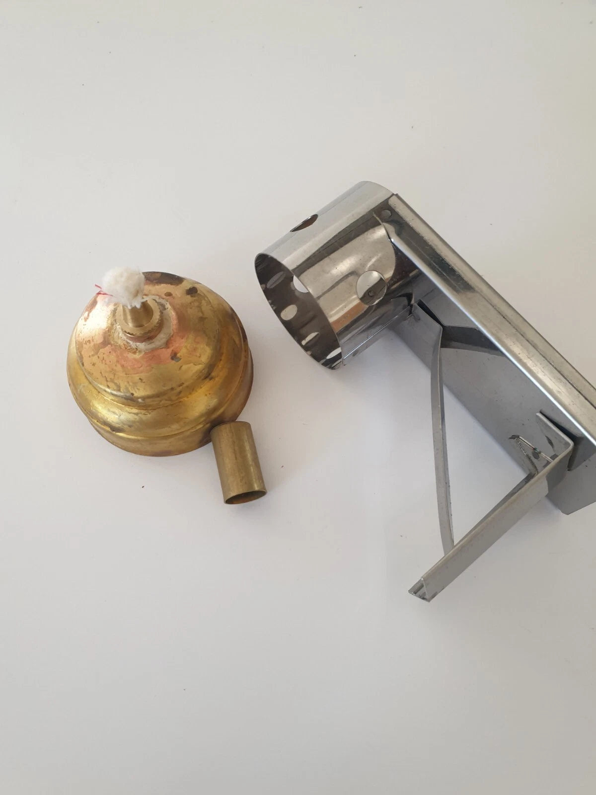 German 2 part brass lamp base with a wick and a polished chrome stand to rest irons,  shown on a plain white background.
