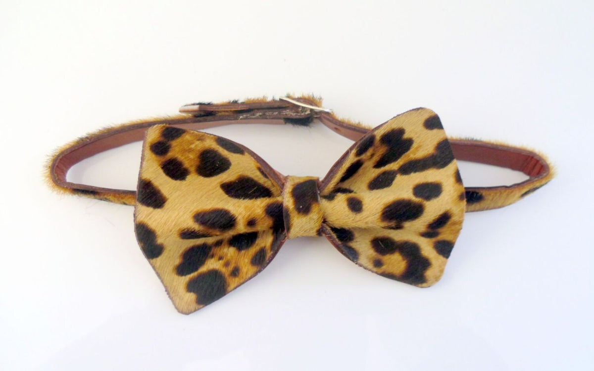 A leopard print faux fur bow tie with a matching brown leather adjustable strap, displayed on a clean white background.