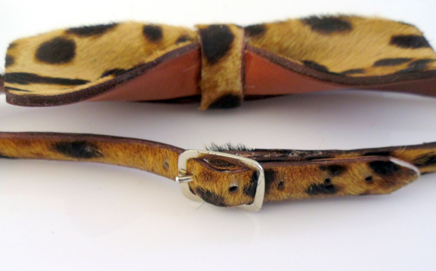 A leopard-print hair-on-hide bow tie and matching belt set with a silver-tone buckle, displayed on a clean white background.