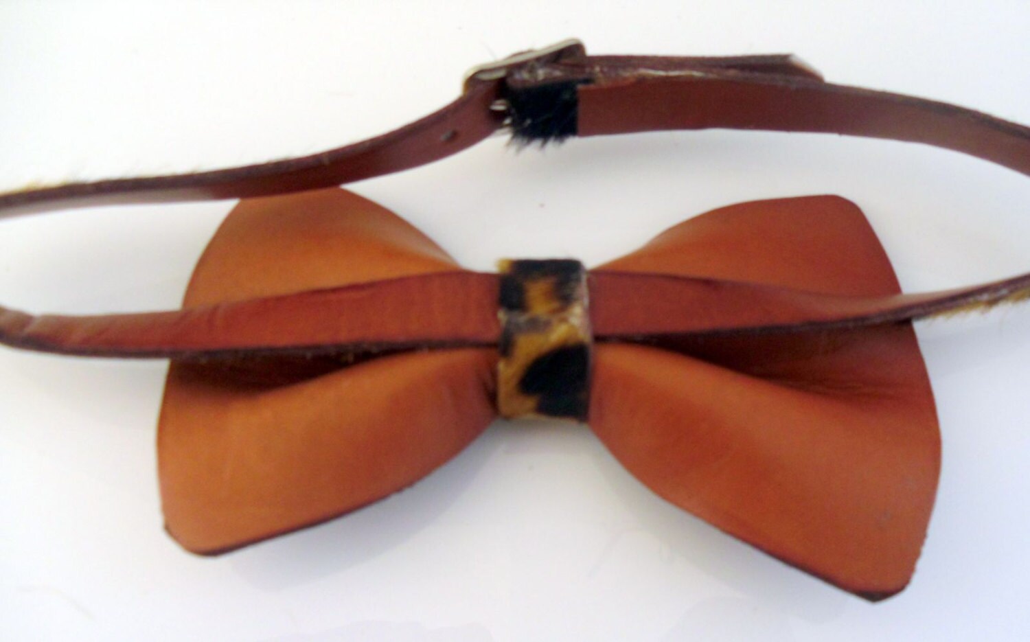 Back of the leopard print hair-on bow tie with a matching adjustable neck leather strap and a central leopard-print accent band, shown on a plain white background.