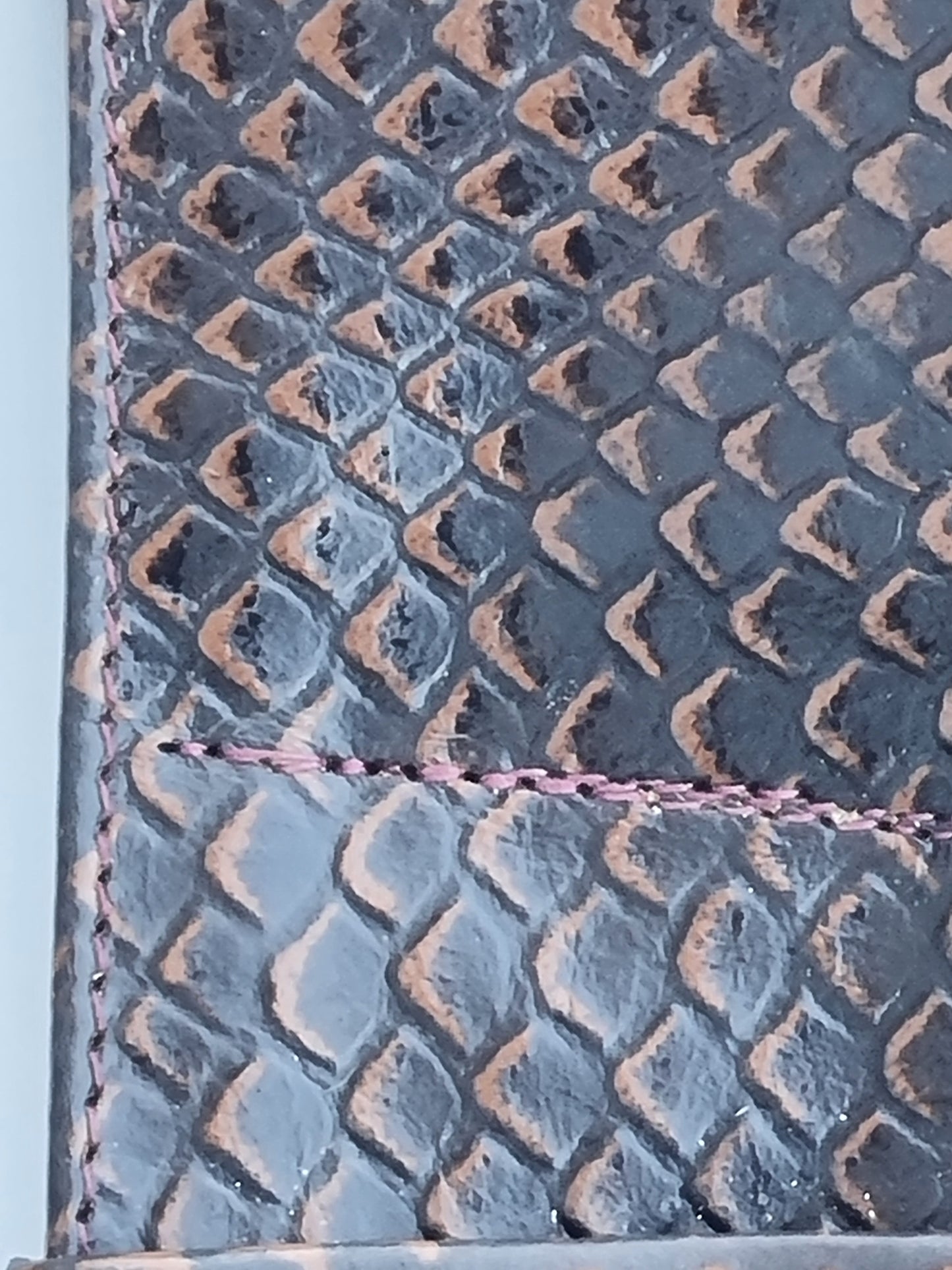 Close-up of a rattle snake scales featuring brown stitched edge.