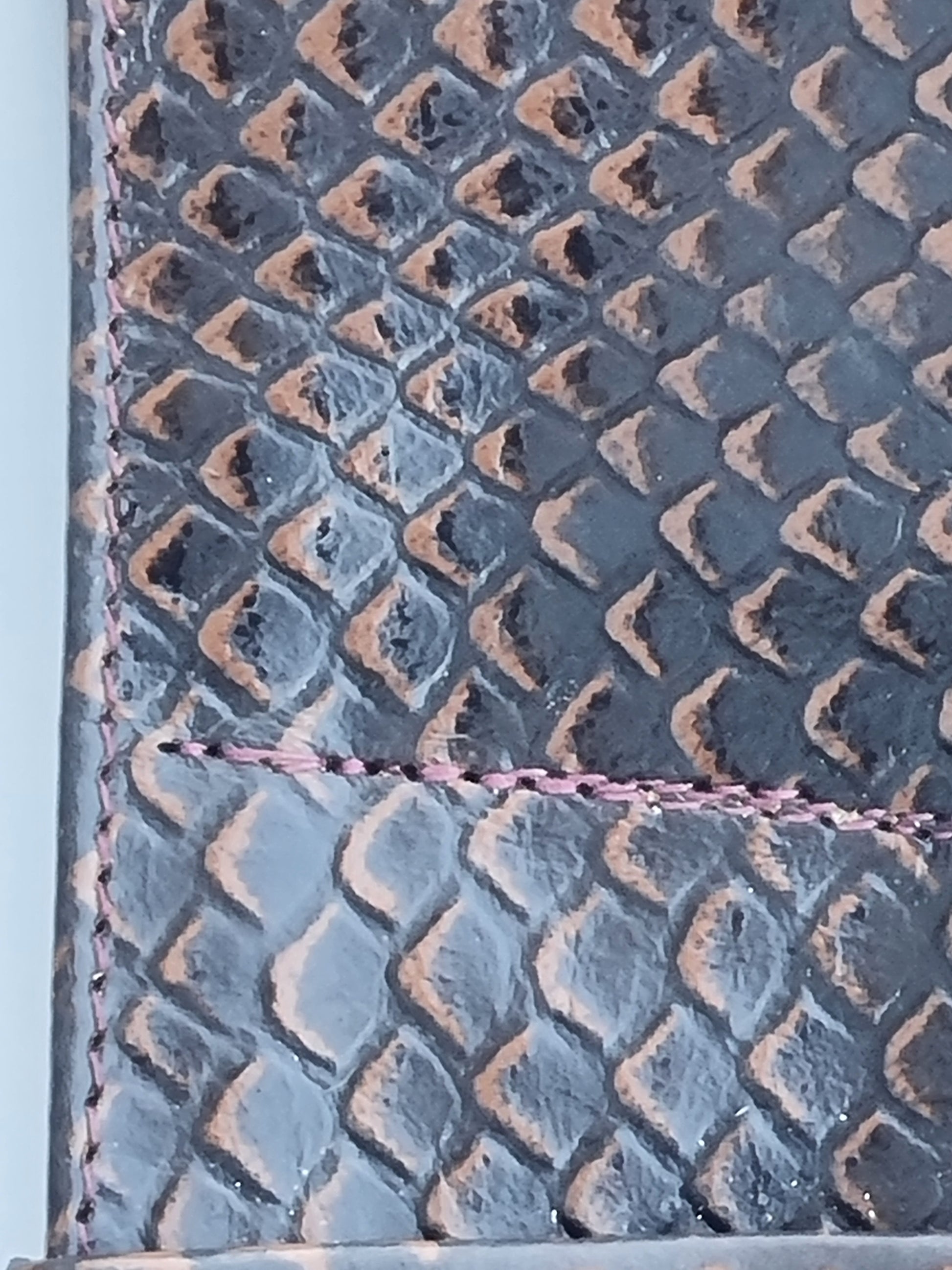 Close-up of a rattle snake scales featuring brown stitched edge.