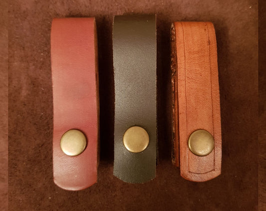 Three types of dandlers for holding knife coloured tan, brown and  natural on brown background
