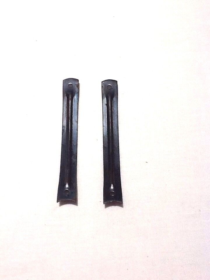 A pair of black steel shanks for boots or shoes laid on a white surface.