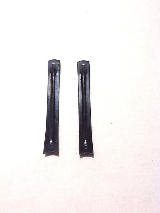 A pair of black steel shanks for boots or shoes laid on a white surface.