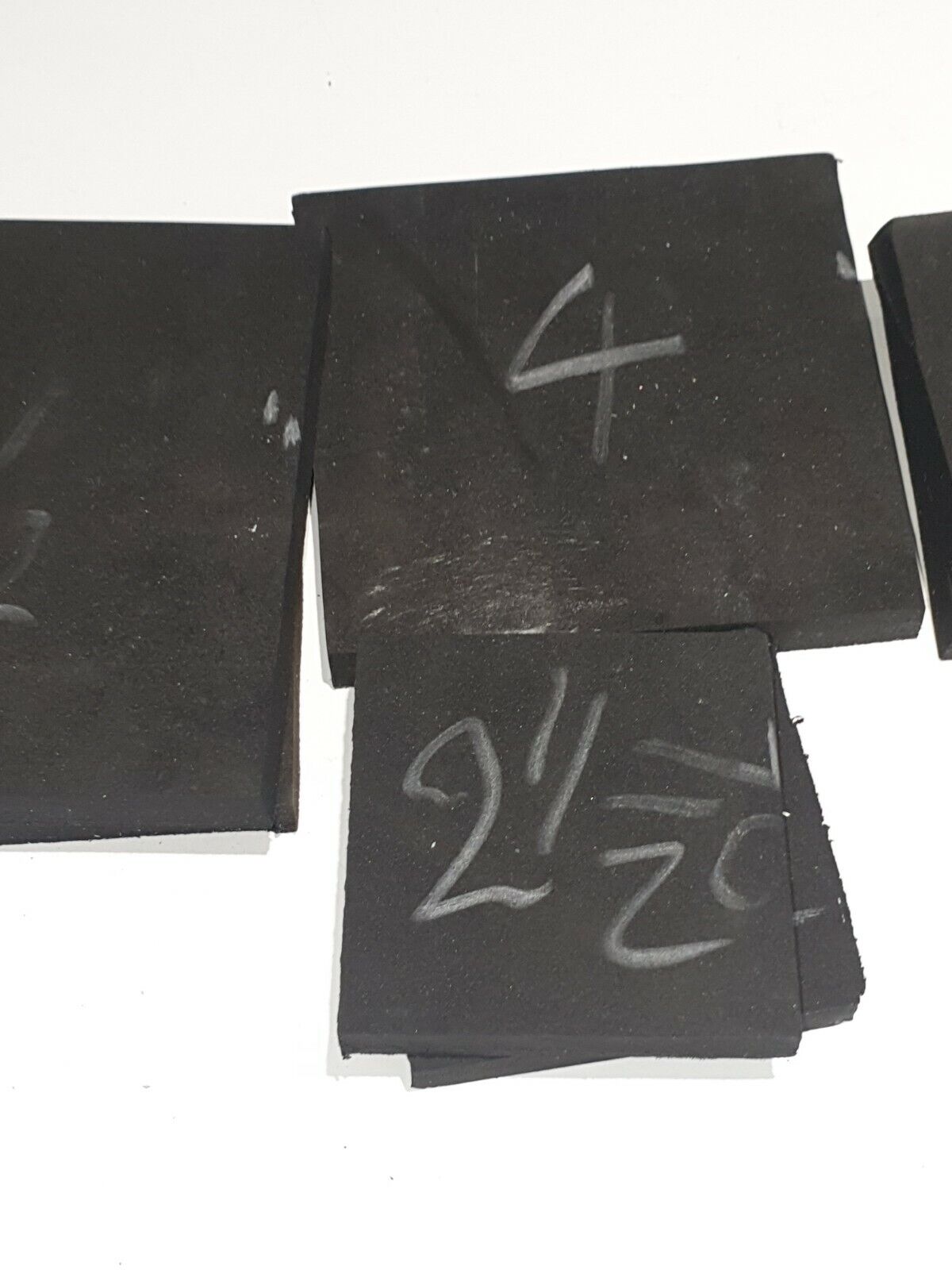 A collection of black micro rubber heels in various sizes and shapes, with some markings on the surface.