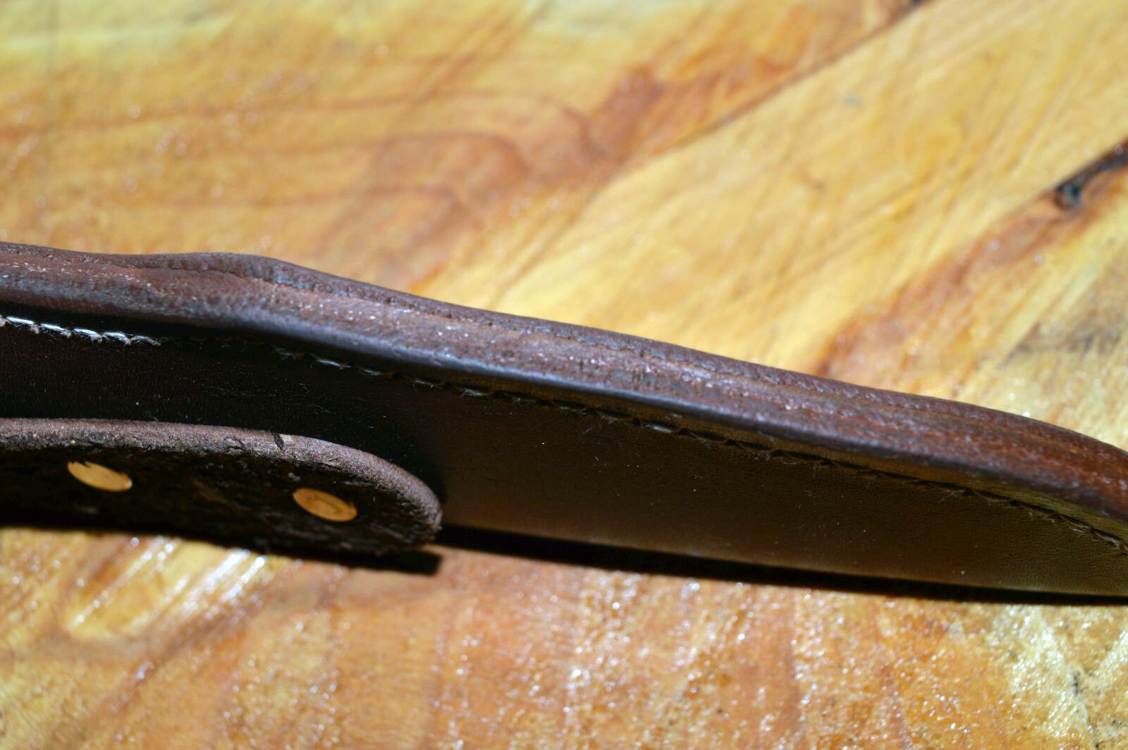 A black leather sheath for a Morakniv 860 type knife showing welt thickness on wooden background
