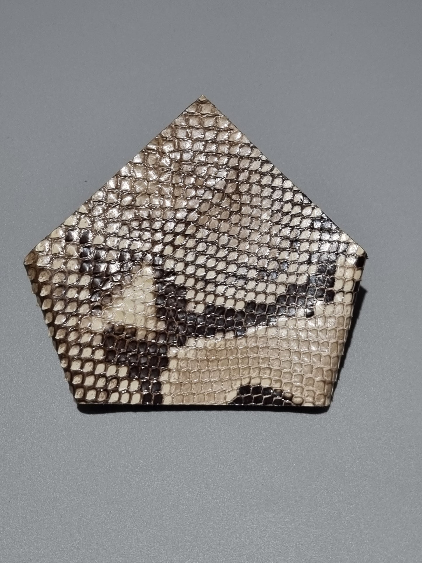 One point suit pocket made from real natural python snakeskin showing natural patterns of brown, beige, and black scales, displayed on a neutral gray background.