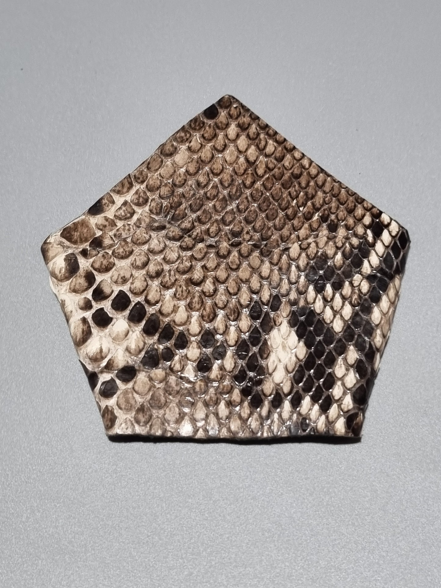 One point suit pocket made from real python snakeskin showing natural patterns of brown, beige, and black scales, displayed on a neutral gray background.