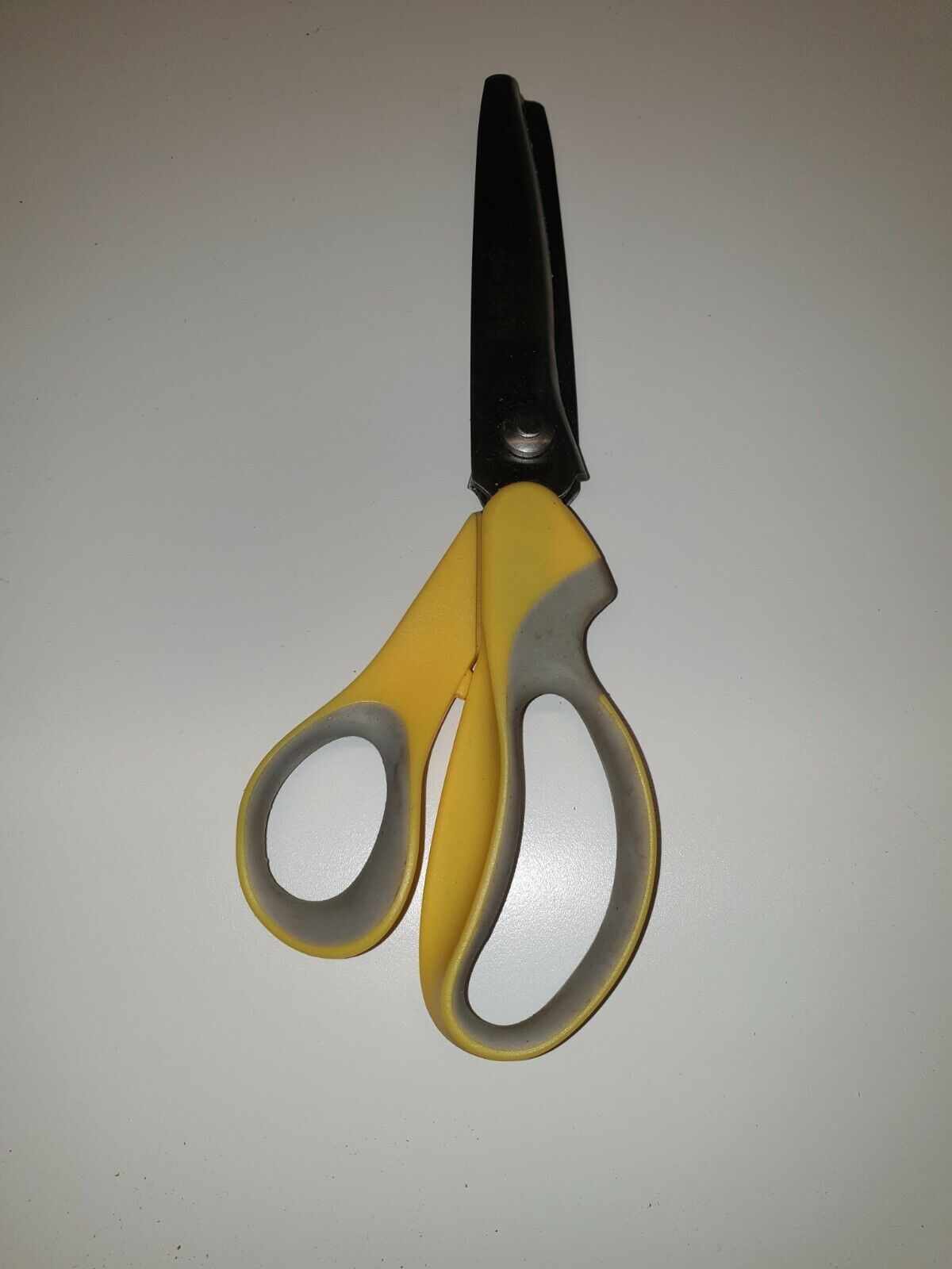 A pair of pinking gimping scissors with yellow and gray plastic handles and a stainless steel blade, designed for leathercraft work.