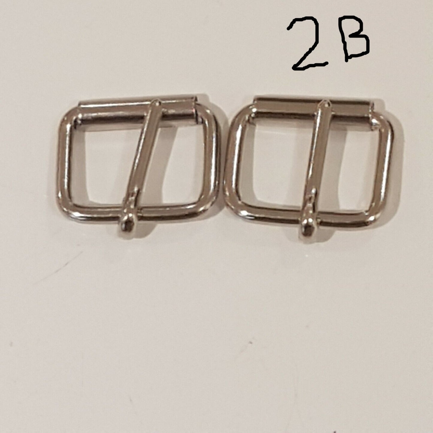 Two metal buckles with a chrome finish on a white background, labelled 2B 