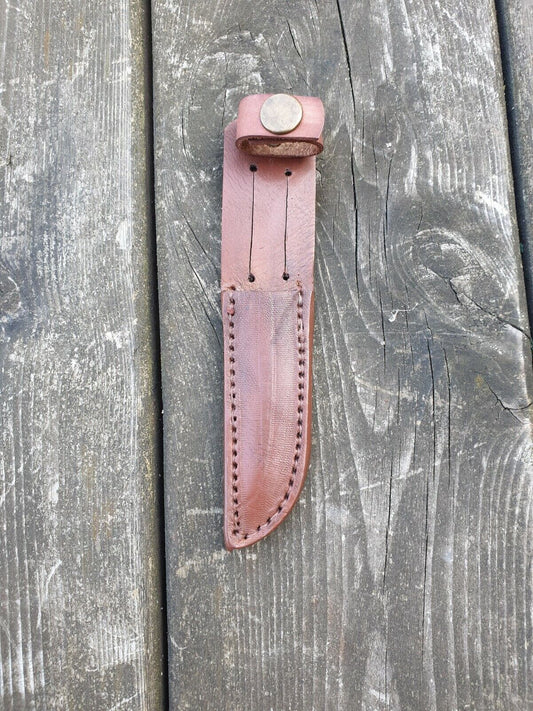 Scout knife sheath in brown colour showing stitching and snap loop on a wooden background