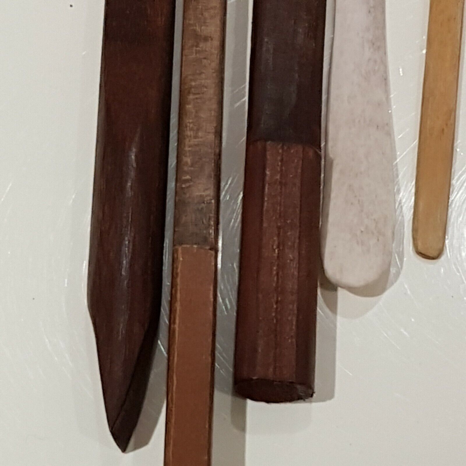 Close view 4 wooden burnishing tools along with cow bone displayed on white back ground